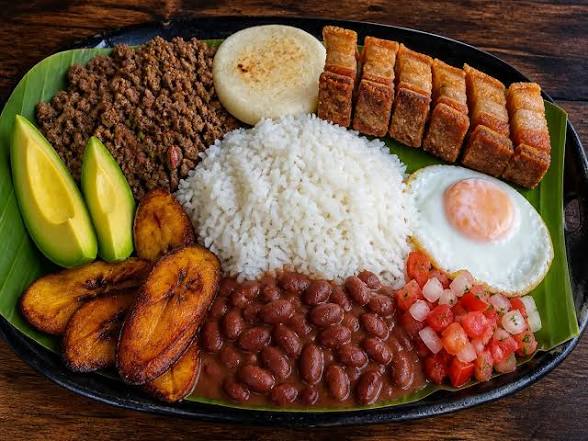 Bandeja paisa con arroz, frijoles, chicharrón, aguacate, huevo y arepa.