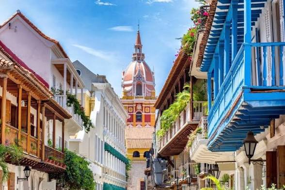 Arquitectura de Cartagena con balcones azules y una torre al fondo.